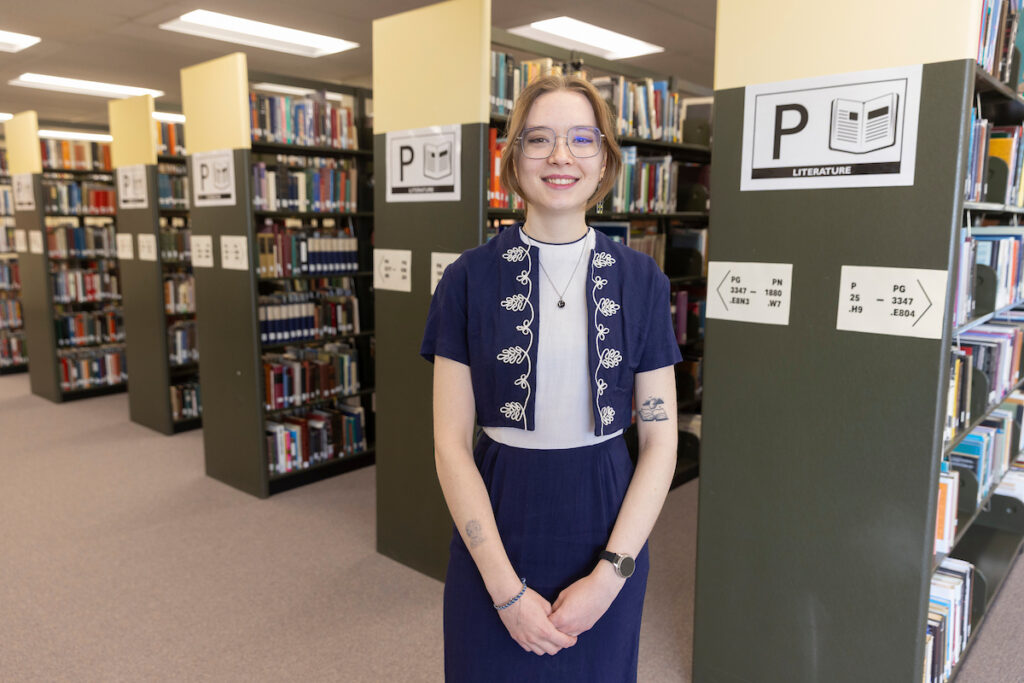 A student studies among bookshelves at the library.